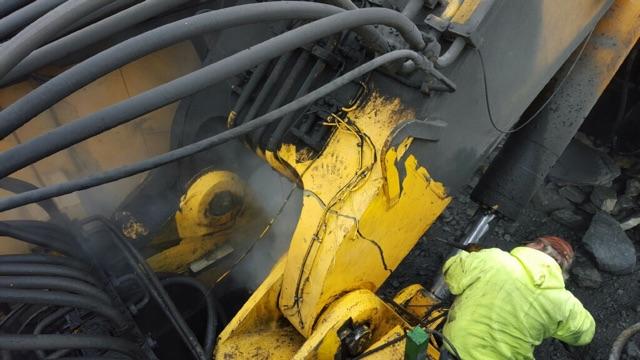 Technician welding a repair on heavy equipment in the field